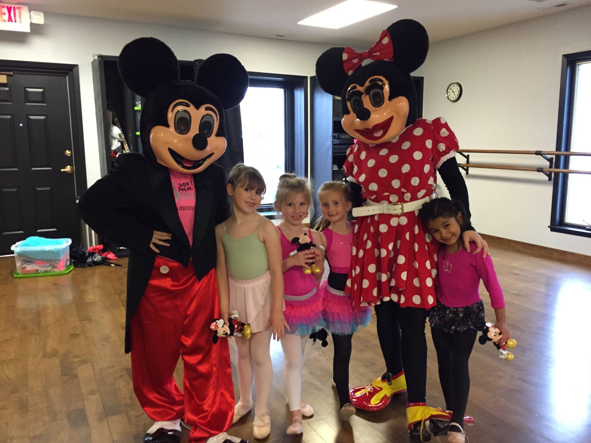 Smiling kids standing with Mickey and Minnie Mouse