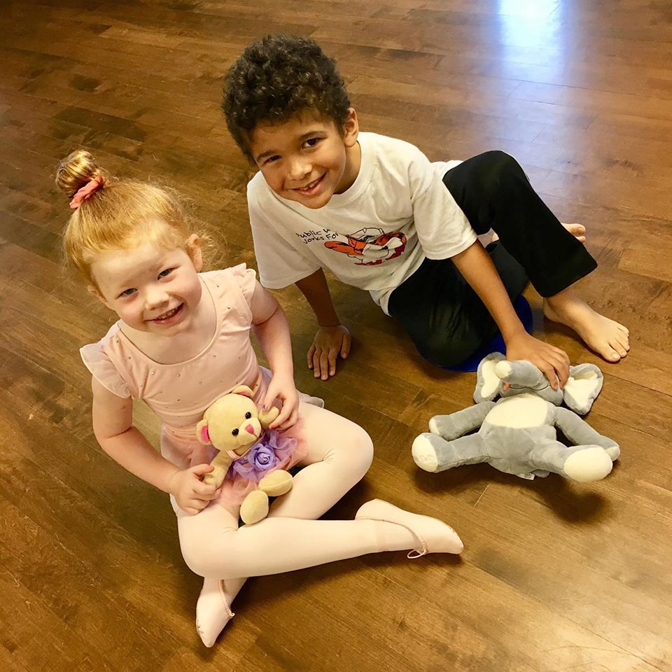 A boy and a girl smiling with stuffed animals